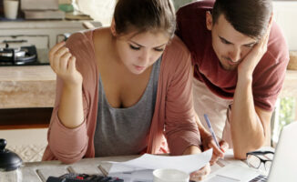 Image of a young couple calculating their budget together in the kitchen