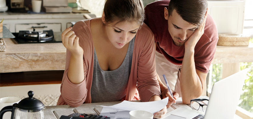 Image of a young couple calculating their budget together in the kitchen