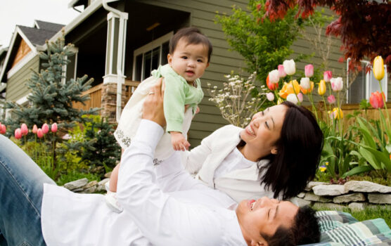 Photo of a young couple and their child in front of their home