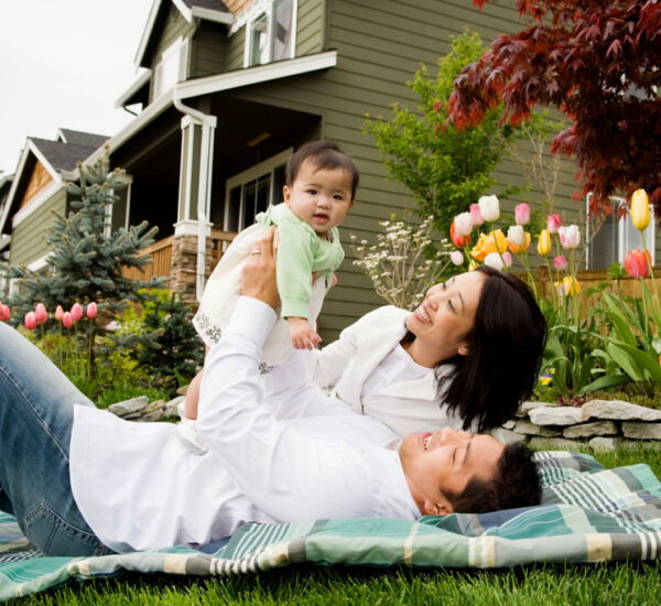 Photo of a young couple and their child in front of their home