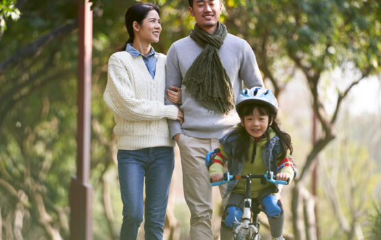 Photo of a young couple and their child riding a bike