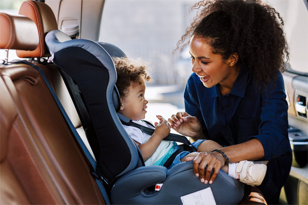 Image of a mom buckling her daughter into a car seat