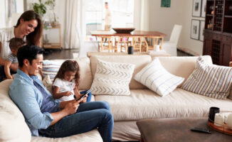 Image of mom and dad with their two young children gathered in the living room of the house