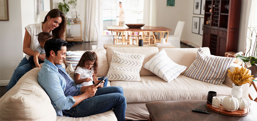 Image of mom and dad with their two young children gathered in the living room of the house